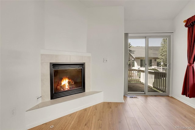 unfurnished living room featuring wood finished floors, a fireplace, and baseboards
