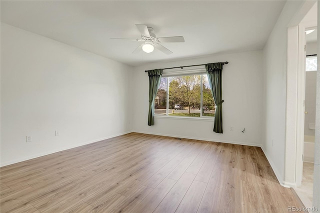 unfurnished room with ceiling fan, light wood-style floors, and baseboards