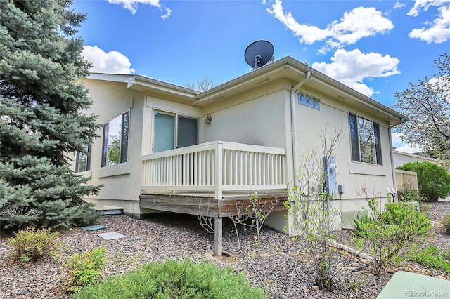 view of side of home with a wooden deck and stucco siding
