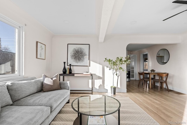 living room featuring beamed ceiling, baseboard heating, and light hardwood / wood-style flooring