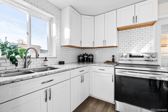 kitchen featuring stainless steel range with electric stovetop, sink, decorative backsplash, and white cabinets