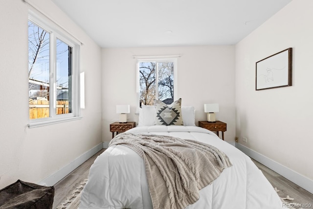 bedroom with multiple windows and light hardwood / wood-style floors