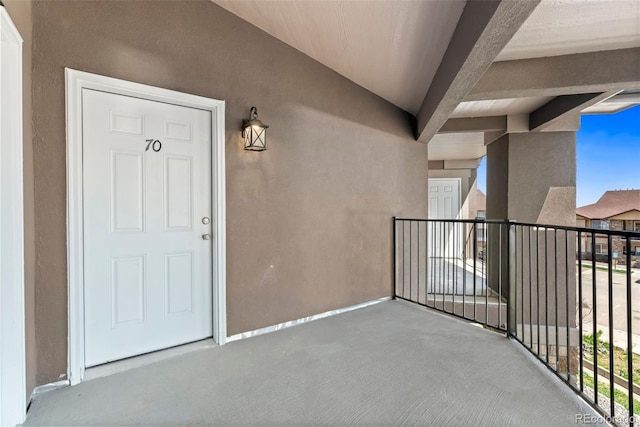 property entrance with a balcony and stucco siding