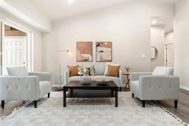 living room with lofted ceiling, light wood-style flooring, and baseboards