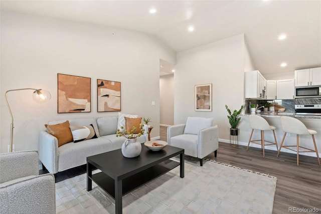 living room with light wood finished floors, baseboards, high vaulted ceiling, and recessed lighting