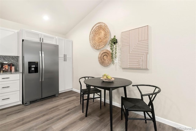 kitchen with vaulted ceiling, white cabinets, wood finished floors, and stainless steel fridge with ice dispenser