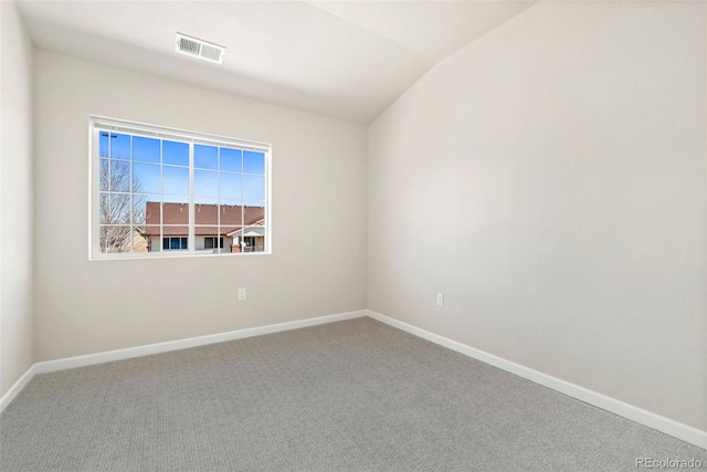 empty room featuring carpet, visible vents, vaulted ceiling, and baseboards