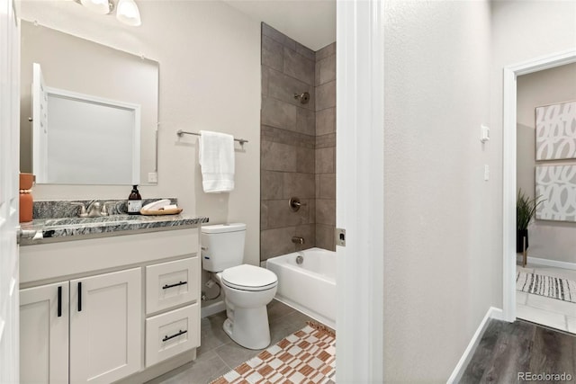 bathroom featuring toilet, washtub / shower combination, vanity, tile patterned flooring, and baseboards