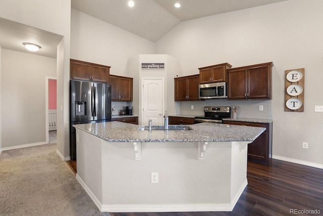 kitchen with a breakfast bar area, a kitchen island with sink, sink, and appliances with stainless steel finishes