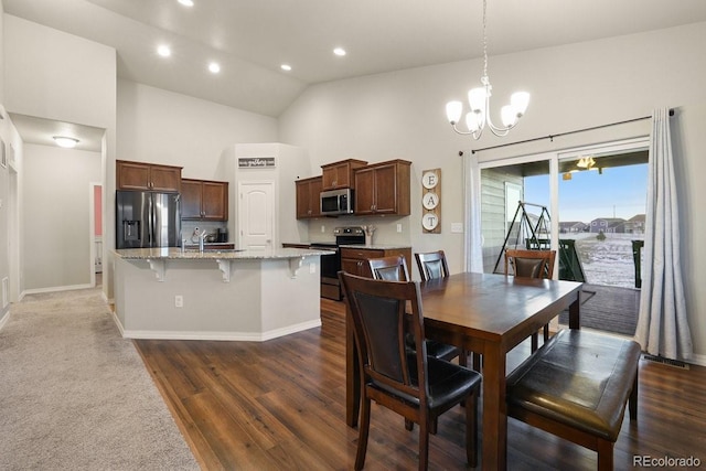 dining area featuring sink, high vaulted ceiling, dark wood-type flooring, and a notable chandelier