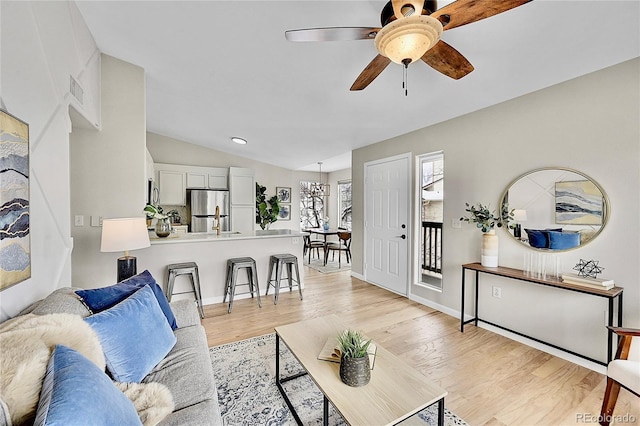 living room with lofted ceiling, light wood finished floors, ceiling fan, and baseboards