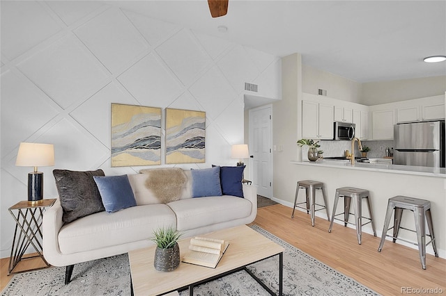 living room featuring baseboards, visible vents, and light wood-style floors