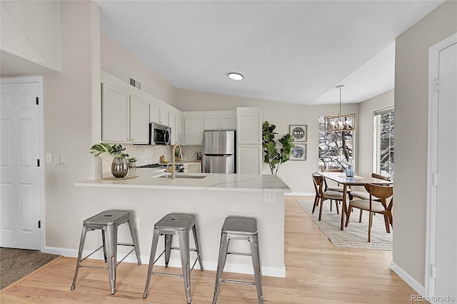 kitchen with a peninsula, visible vents, appliances with stainless steel finishes, and light countertops