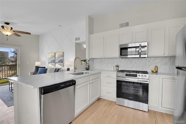 kitchen featuring stainless steel appliances, a peninsula, a sink, visible vents, and light countertops