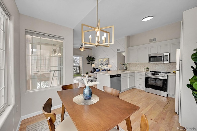 dining space featuring light wood-type flooring, visible vents, a notable chandelier, and baseboards