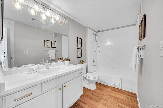 full bath featuring visible vents, shower / bathing tub combination, toilet, vanity, and wood finished floors