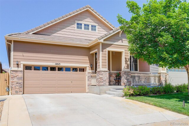 12513 Grape St, Thornton, CO 80241 - craftsman-style home featuring stone siding, a porch, concrete driveway, a tile roof, and a garage