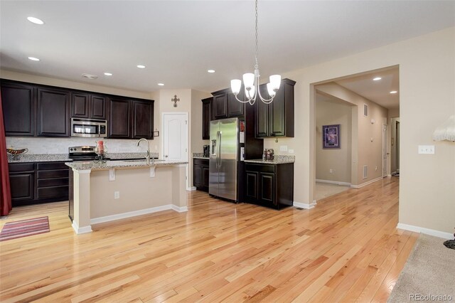 12513 Grape St, Thornton, CO 80241 - kitchen featuring stainless steel appliances, light wood-style flooring, recessed lighting, a breakfast bar, and a chandelier