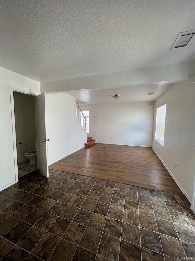 empty room with dark hardwood / wood-style flooring and a textured ceiling