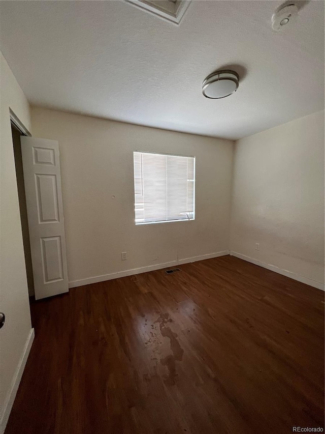 unfurnished room featuring dark hardwood / wood-style flooring and a textured ceiling