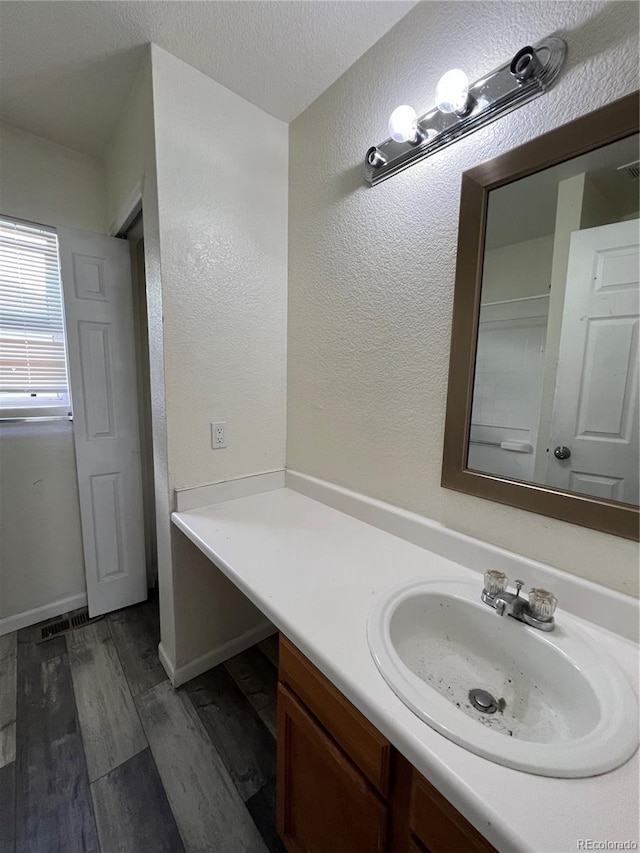 bathroom featuring hardwood / wood-style flooring, vanity, and a textured ceiling