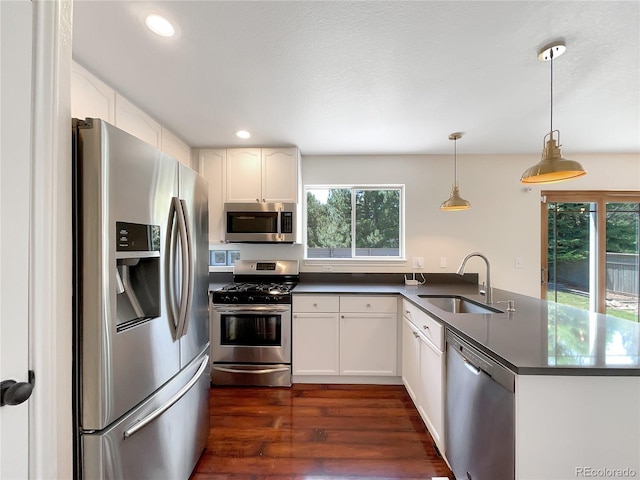 kitchen featuring white cabinets, hanging light fixtures, sink, appliances with stainless steel finishes, and kitchen peninsula