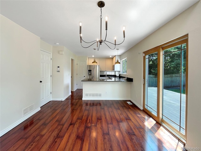 kitchen with kitchen peninsula, stainless steel refrigerator with ice dispenser, dark hardwood / wood-style flooring, sink, and decorative light fixtures