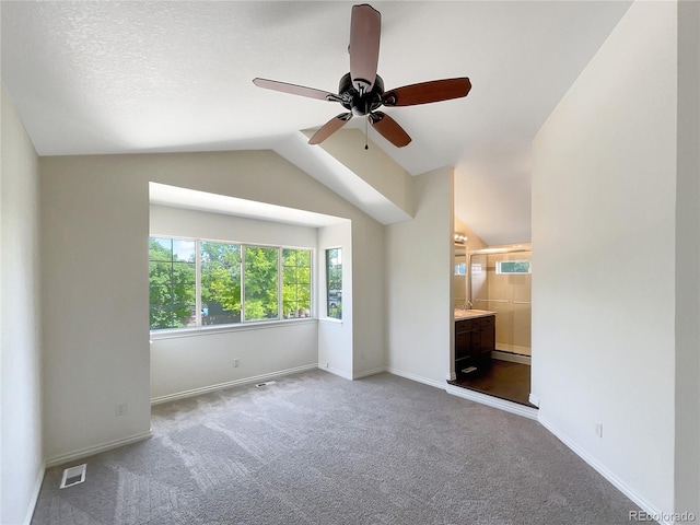 interior space featuring lofted ceiling, ceiling fan, baseboard heating, connected bathroom, and carpet floors