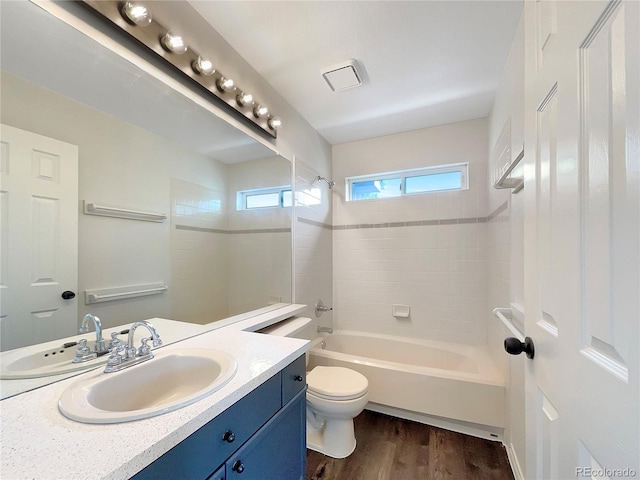 full bathroom with vanity, hardwood / wood-style flooring, toilet, and tiled shower / bath