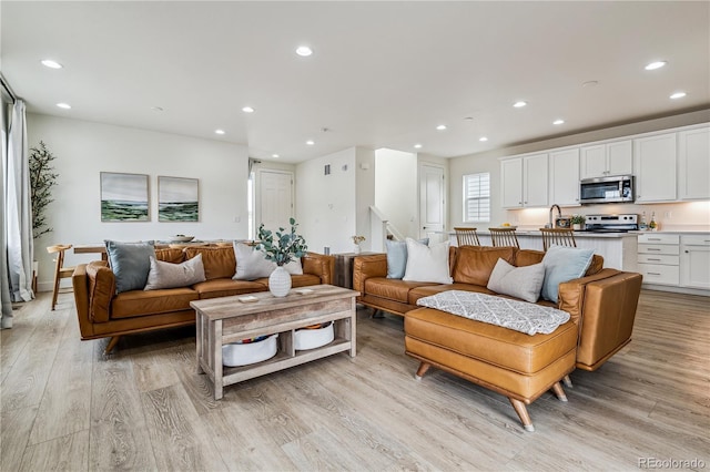 living area with light wood-style flooring and recessed lighting