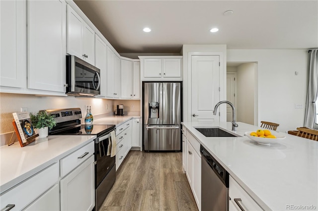 kitchen with light countertops, light wood-style flooring, stainless steel appliances, recessed lighting, and a sink