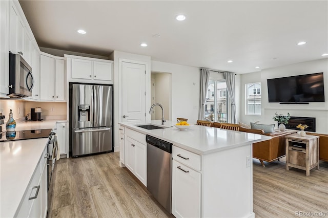 kitchen with a sink, appliances with stainless steel finishes, light wood-style flooring, white cabinets, and recessed lighting