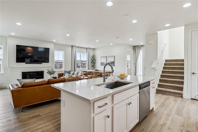 kitchen featuring dishwasher, light countertops, a sink, and light wood-style floors