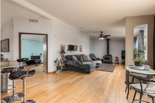 living room with hardwood / wood-style flooring, ceiling fan, and a wood stove