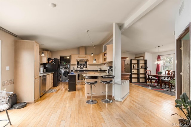 kitchen with decorative light fixtures, a kitchen island, a breakfast bar, and appliances with stainless steel finishes