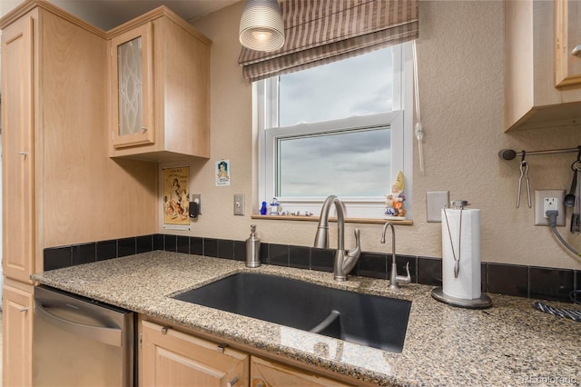 kitchen featuring stainless steel dishwasher, light stone countertops, sink, and light brown cabinets