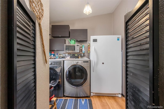 laundry room with light hardwood / wood-style flooring and washer and dryer