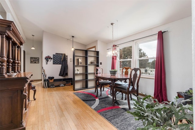 dining room featuring lofted ceiling, a notable chandelier, and light hardwood / wood-style floors