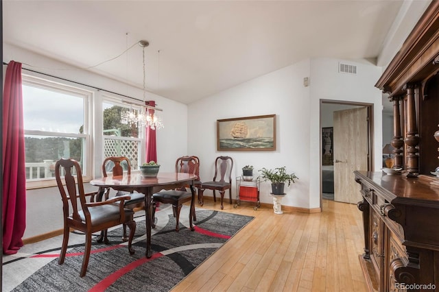 dining area featuring lofted ceiling, an inviting chandelier, and light hardwood / wood-style flooring