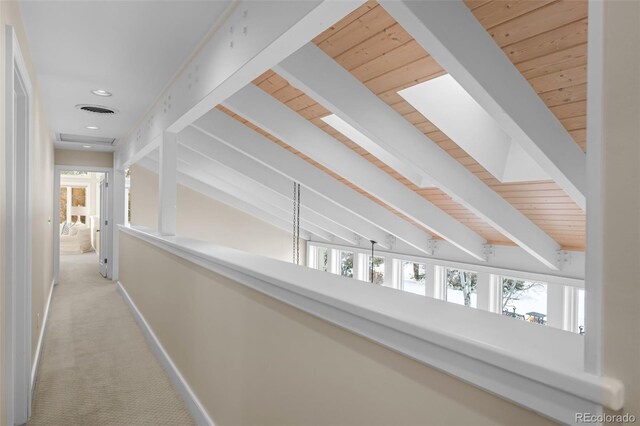 hall with baseboards, carpet flooring, wood ceiling, and beam ceiling