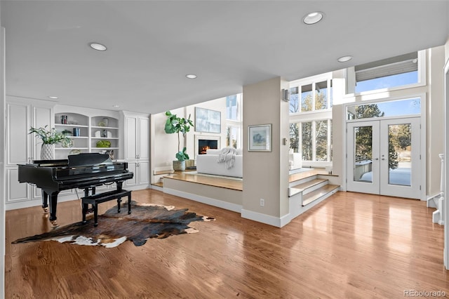 sitting room featuring built in features, french doors, recessed lighting, and light wood-style flooring