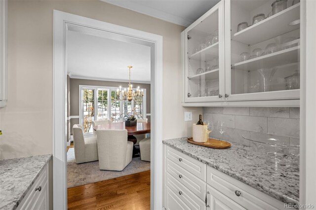 bar with crown molding, an inviting chandelier, backsplash, and dark wood-style floors