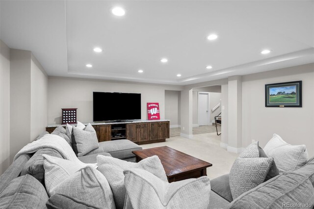 living room featuring stairway, a tray ceiling, recessed lighting, and light colored carpet