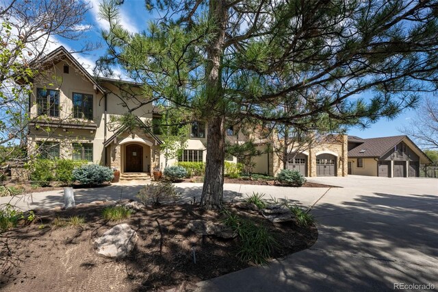 view of front of home featuring curved driveway, stucco siding, and stone siding