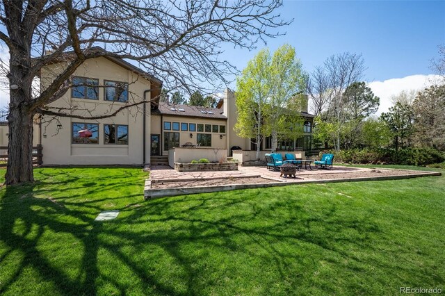 rear view of house with a lawn, stucco siding, and a patio area