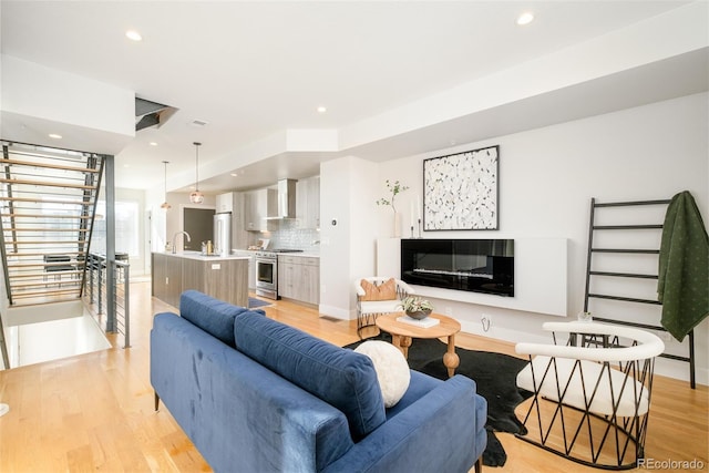 living room featuring sink and light hardwood / wood-style flooring