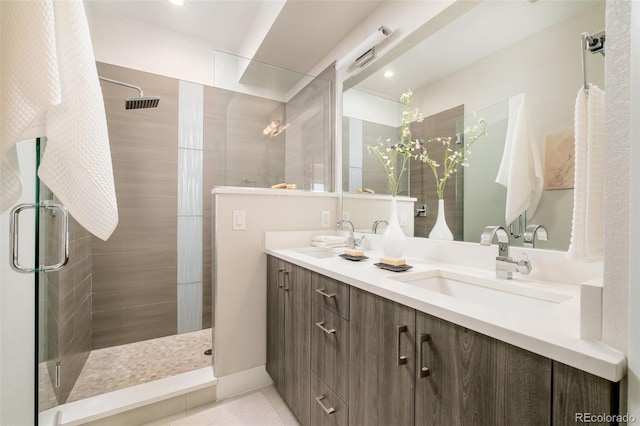 full bath with a shower stall, double vanity, tile patterned floors, and a sink