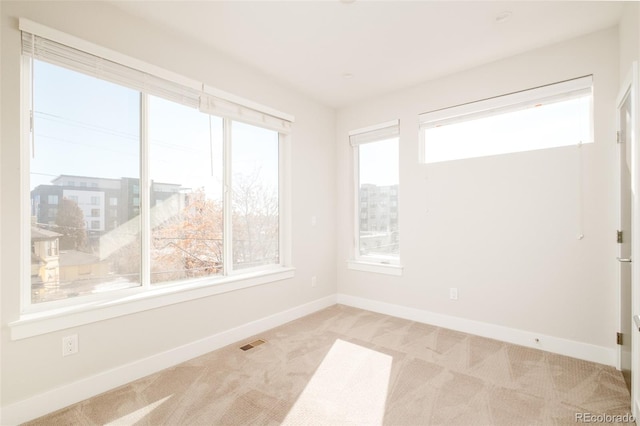 spare room featuring visible vents, light colored carpet, and baseboards