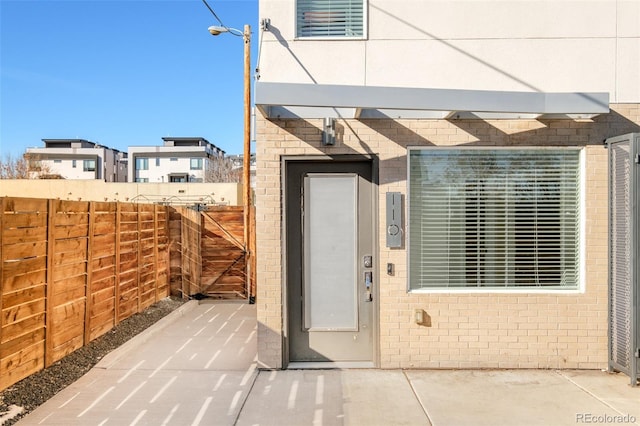 entrance to property with fence and brick siding