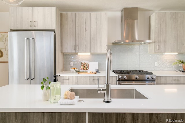 kitchen with stainless steel appliances, light countertops, wall chimney range hood, and modern cabinets